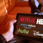 Personne comparant les logos des services de streaming (Netflix, Disney+) sur une tablette pour trouver le meilleur IPTV.