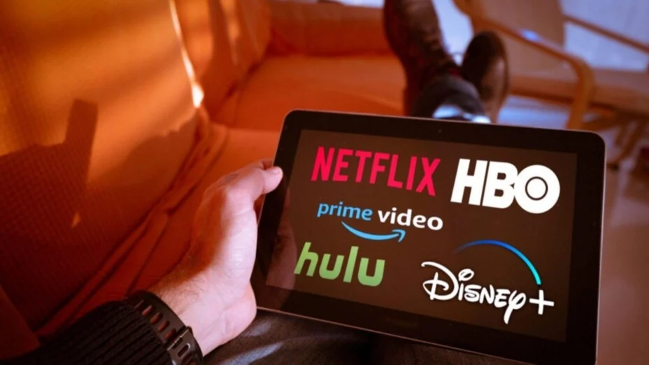 Personne comparant les logos des services de streaming (Netflix, Disney+) sur une tablette pour trouver le meilleur IPTV.